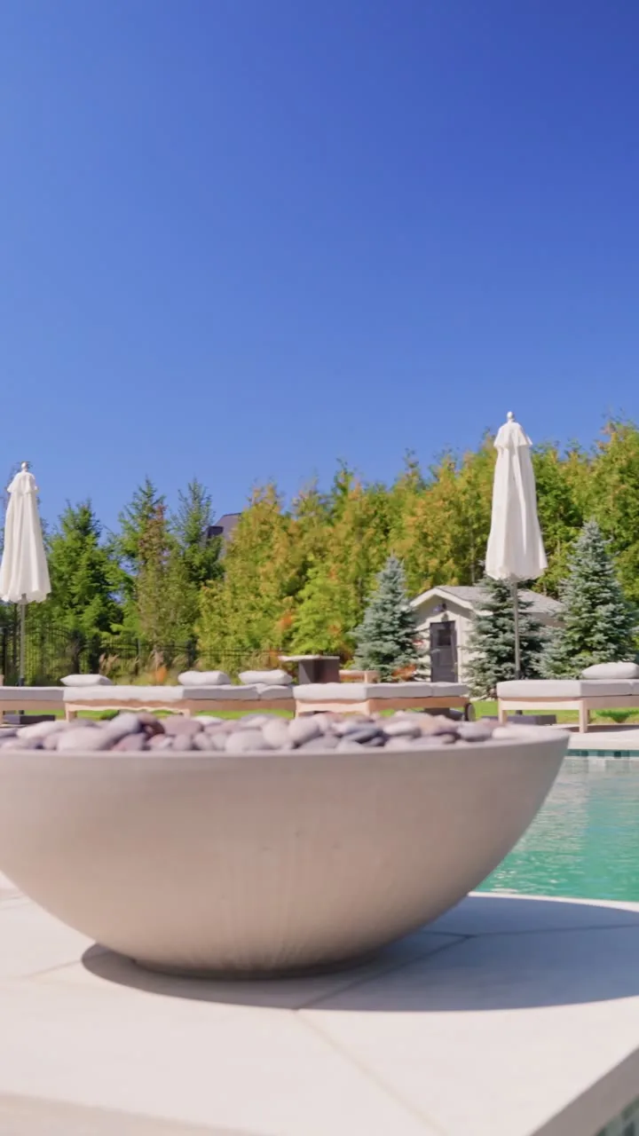 A concrete fire bowl beside a pool, one of the devices AVAS Automation connected to the same app as the rest of the home
