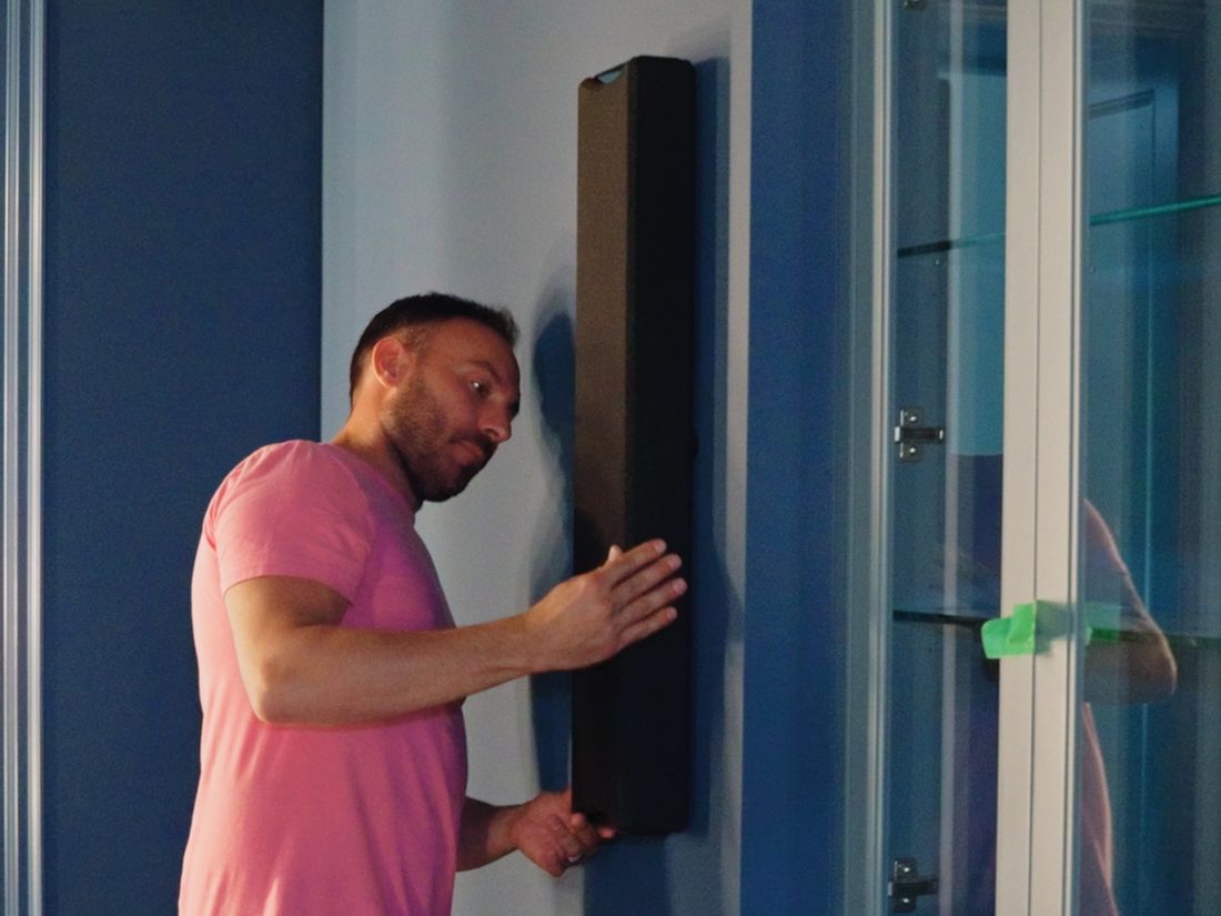 An AVAS technician mounting a slim speaker on the theatre wall