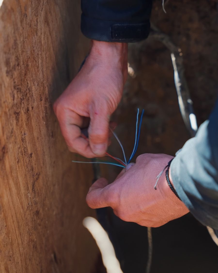 An AVAS technician splicing low voltage camera wires inside an excavated trench