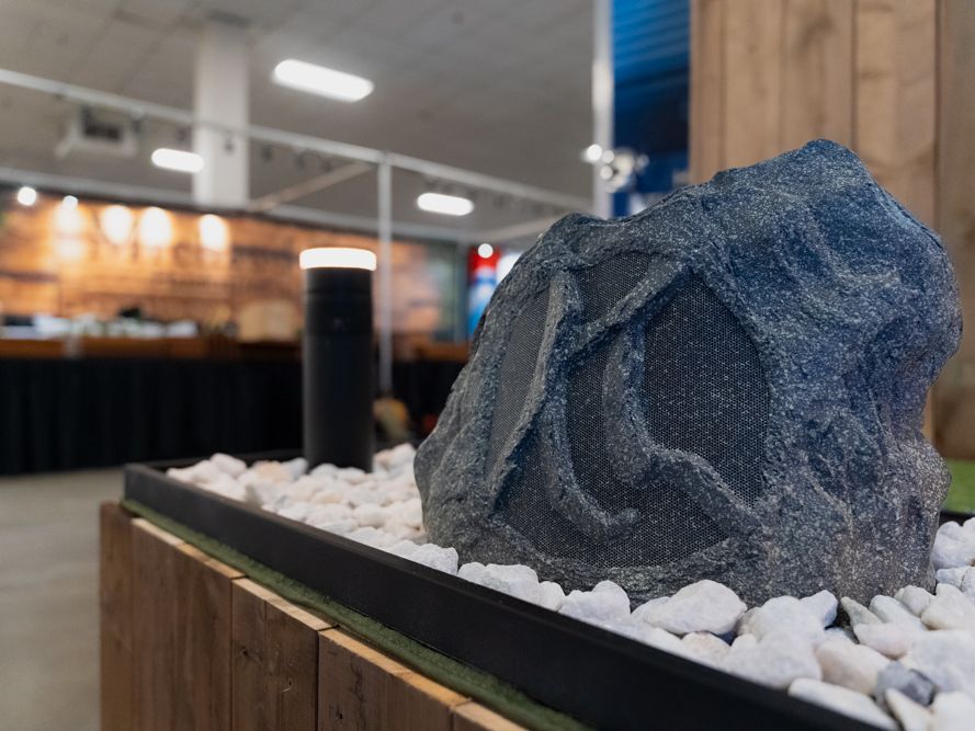 A rock speaker that looks like a natural stone, set in white landscape stones
