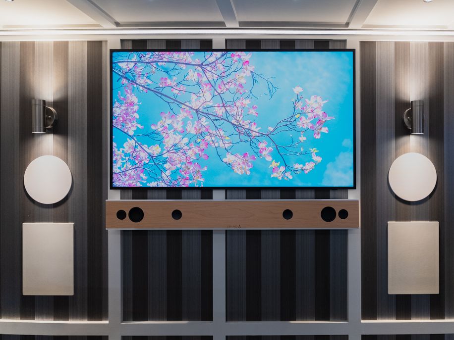 Lounge wall with a TV, soundbar, wall sconces, and hidden speakers inside the trailer