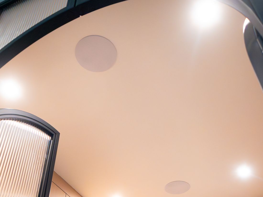 Flush in-ceiling speakers and pot lights in a warm wood toned office ceiling