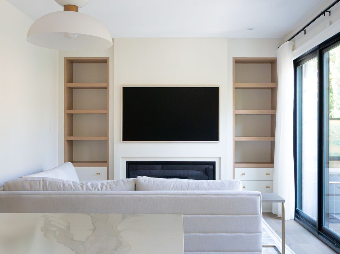 An open kitchen and family room with a marble island, sofa, and a TV above the fireplace