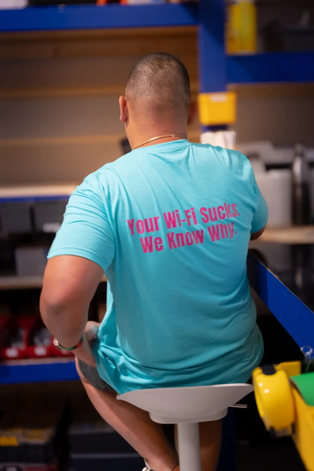 An AVAS team member from behind in a teal shirt reading Your Wi-Fi Sucks. We Know Why.