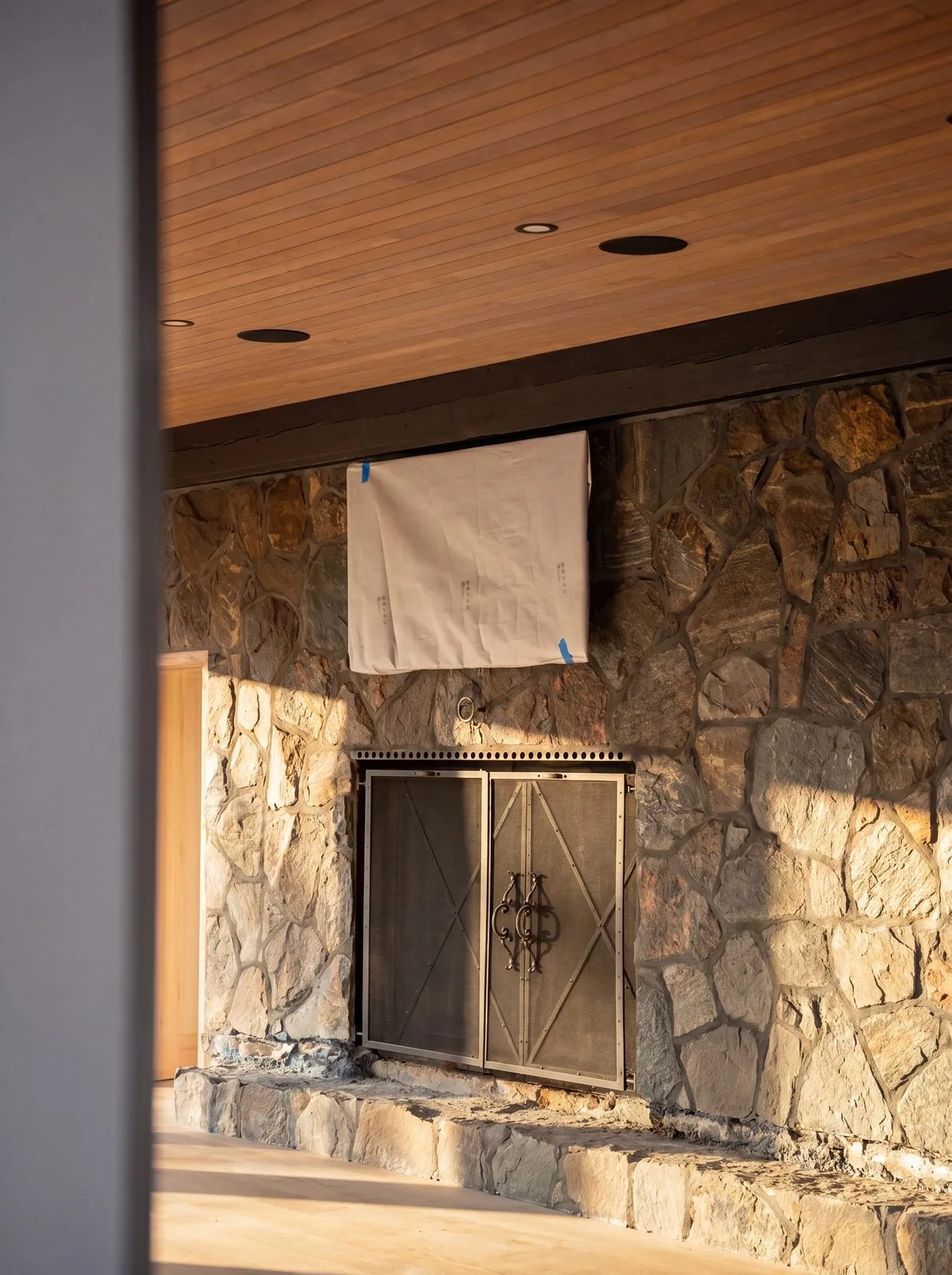 A stone fireplace under a wood plank ceiling in a custom home under construction