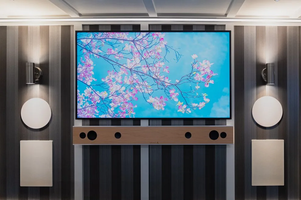 The same lounge wall of the AVAS trailer, framed the same way, with its ceiling lit warm white and the sconces on