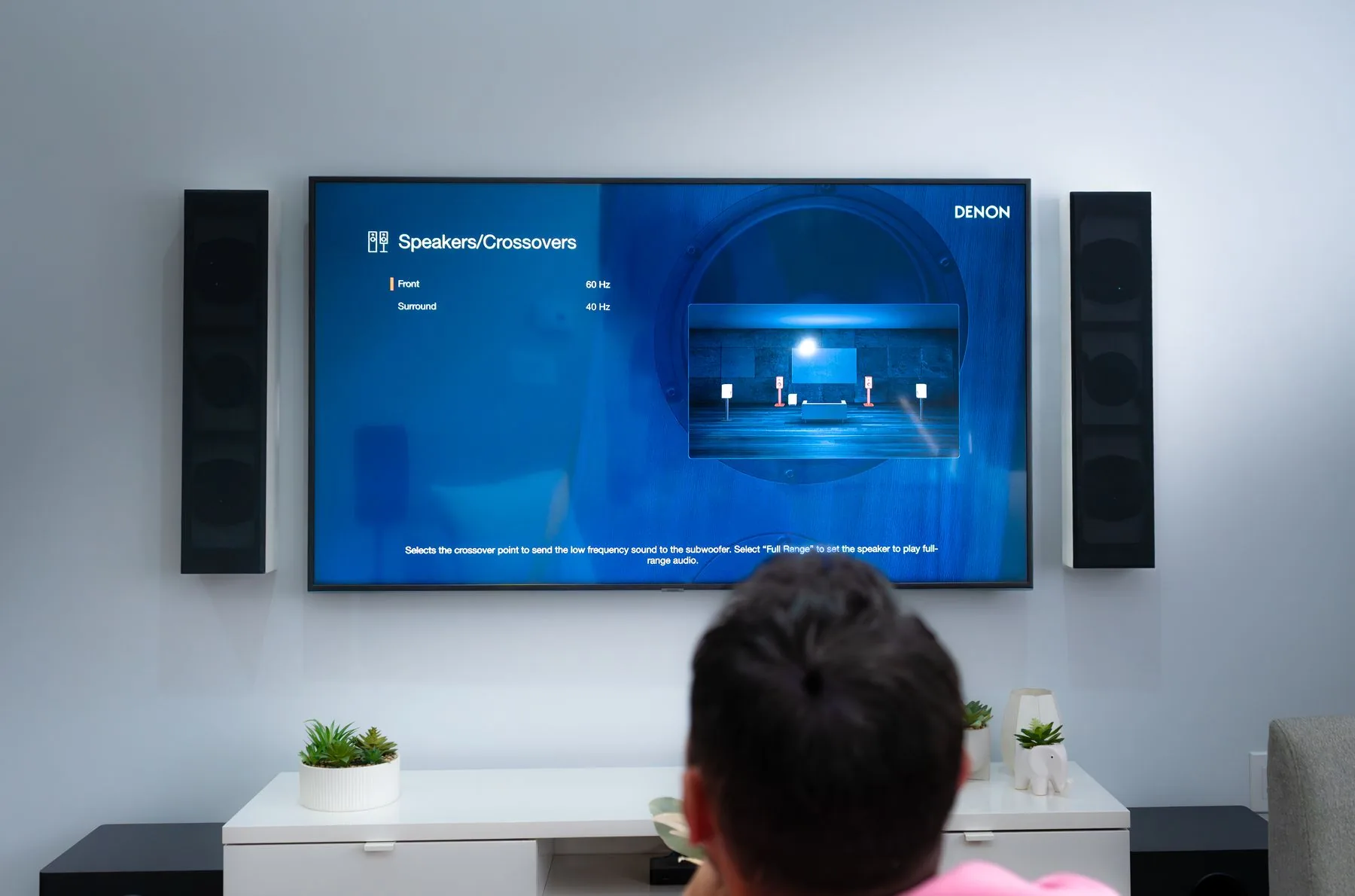 A receiver's speaker setup screen on a living room theatre TV, showing crossover settings for the front and surround speakers