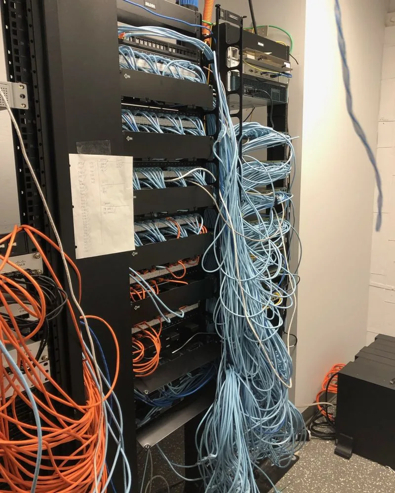 An equipment rack with orange and blue cables hanging loose down the side